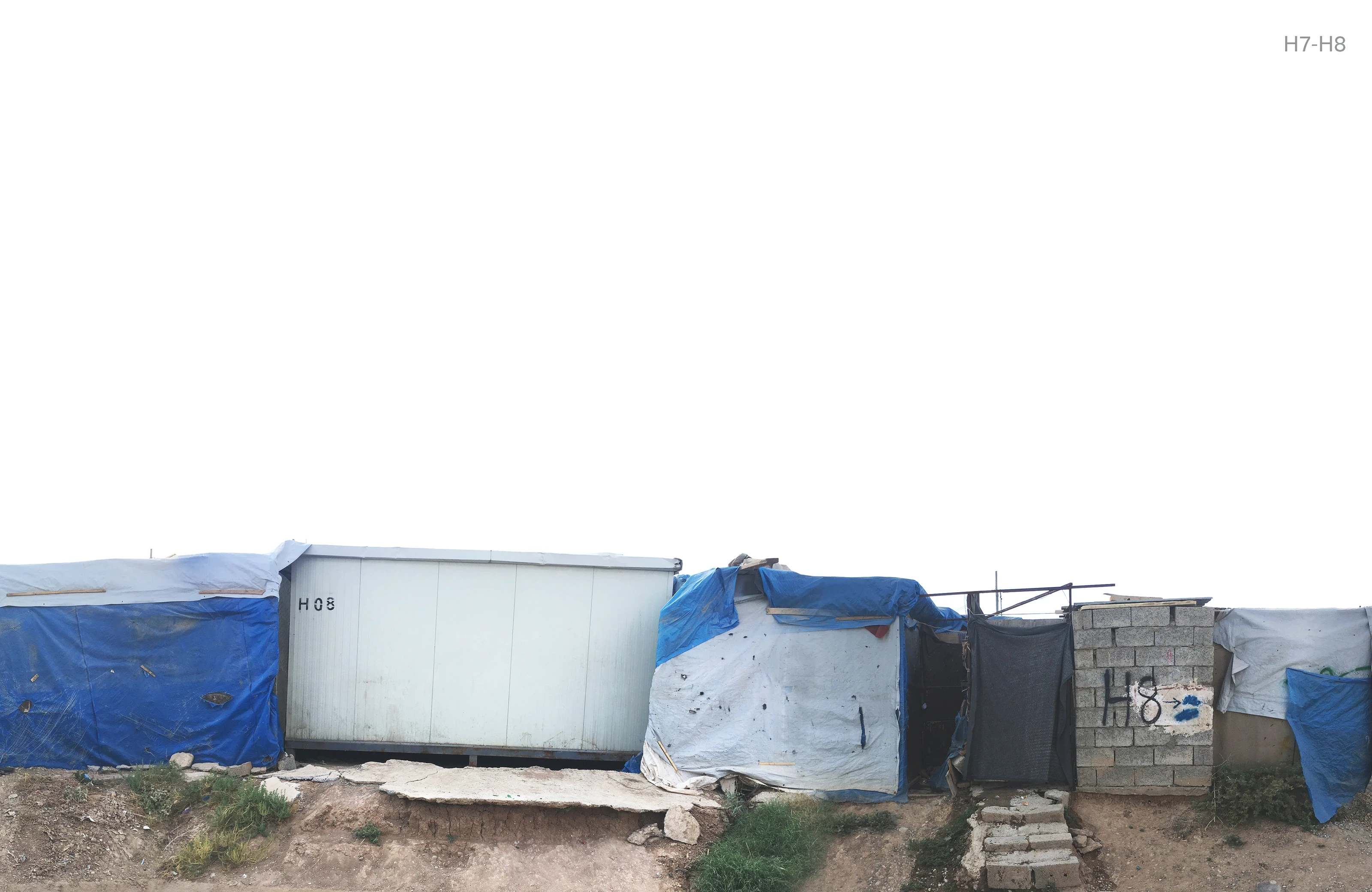 A row of caravan homes extended with metal sheets, a white container and blue tarpaulins.
