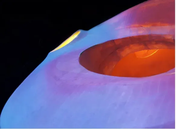 Close-up of the torus’s inner opening glowing orange against a blue-lit surface.