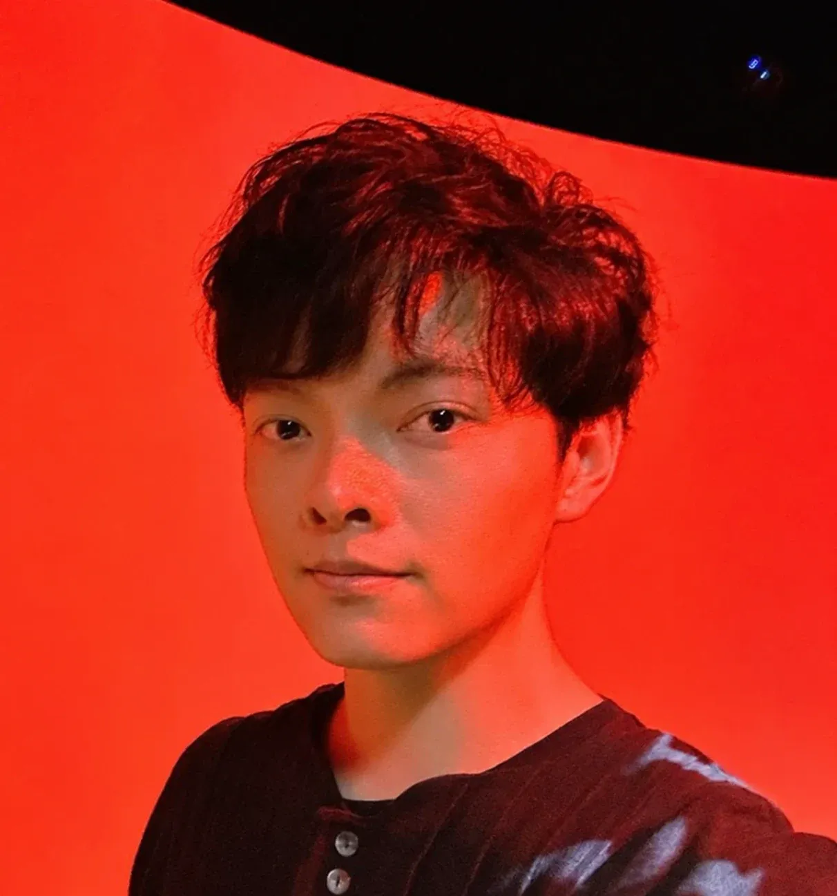 Chien-hua Huang in front of a curved red projection screen.
