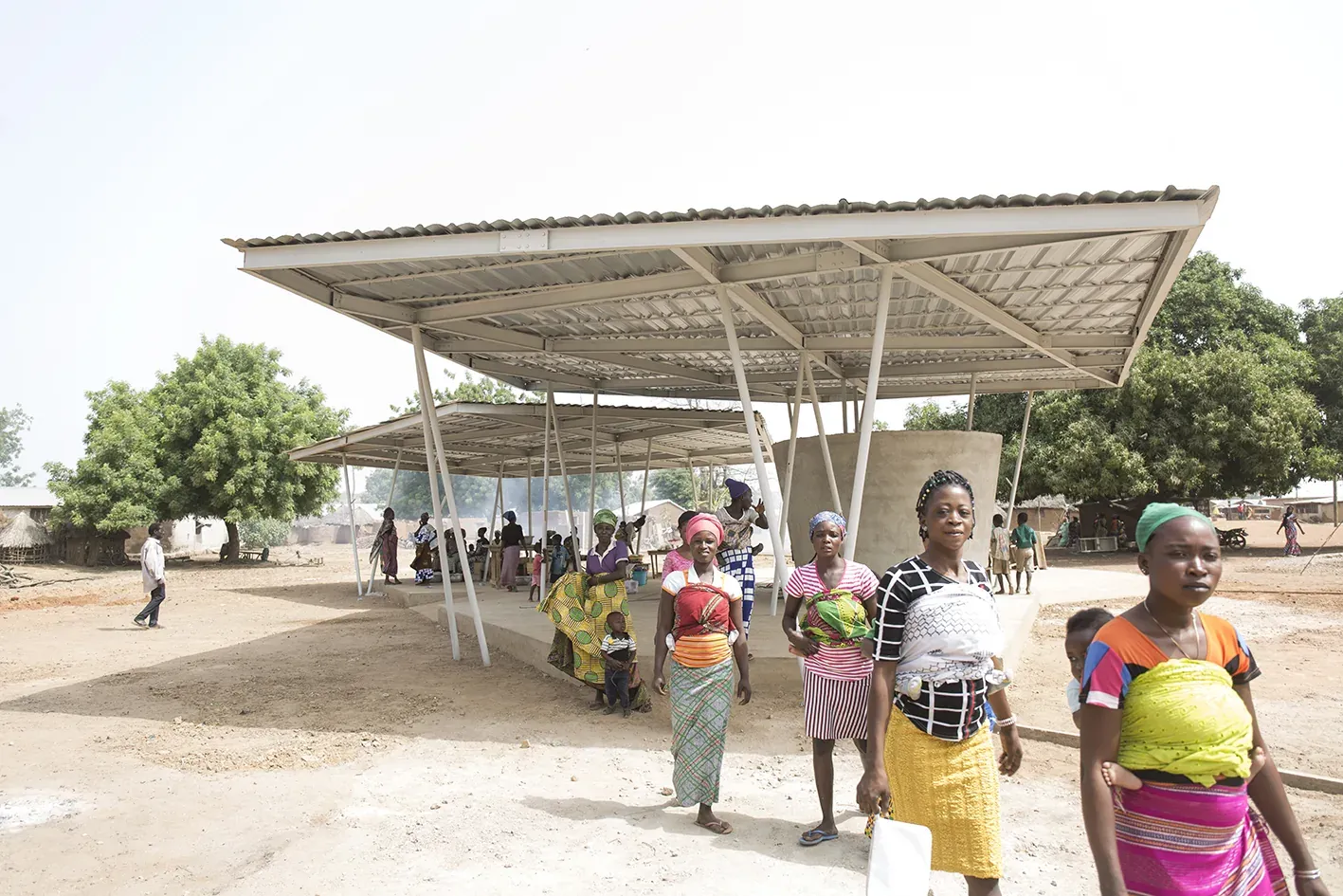 Women carrying goods walk under the market roof.