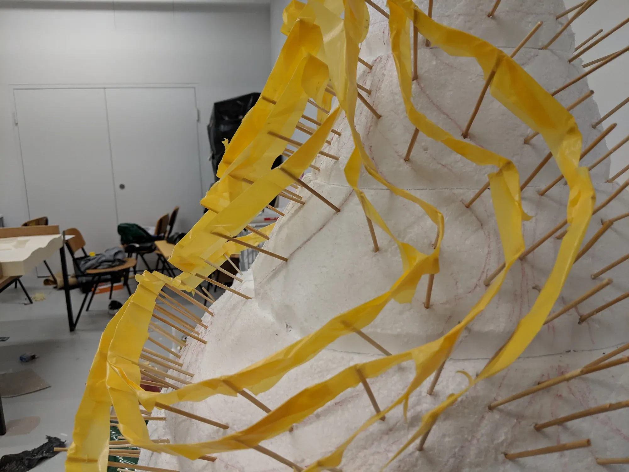 Strips of yellow tape stretched between wooden sticks as temporary ribs.