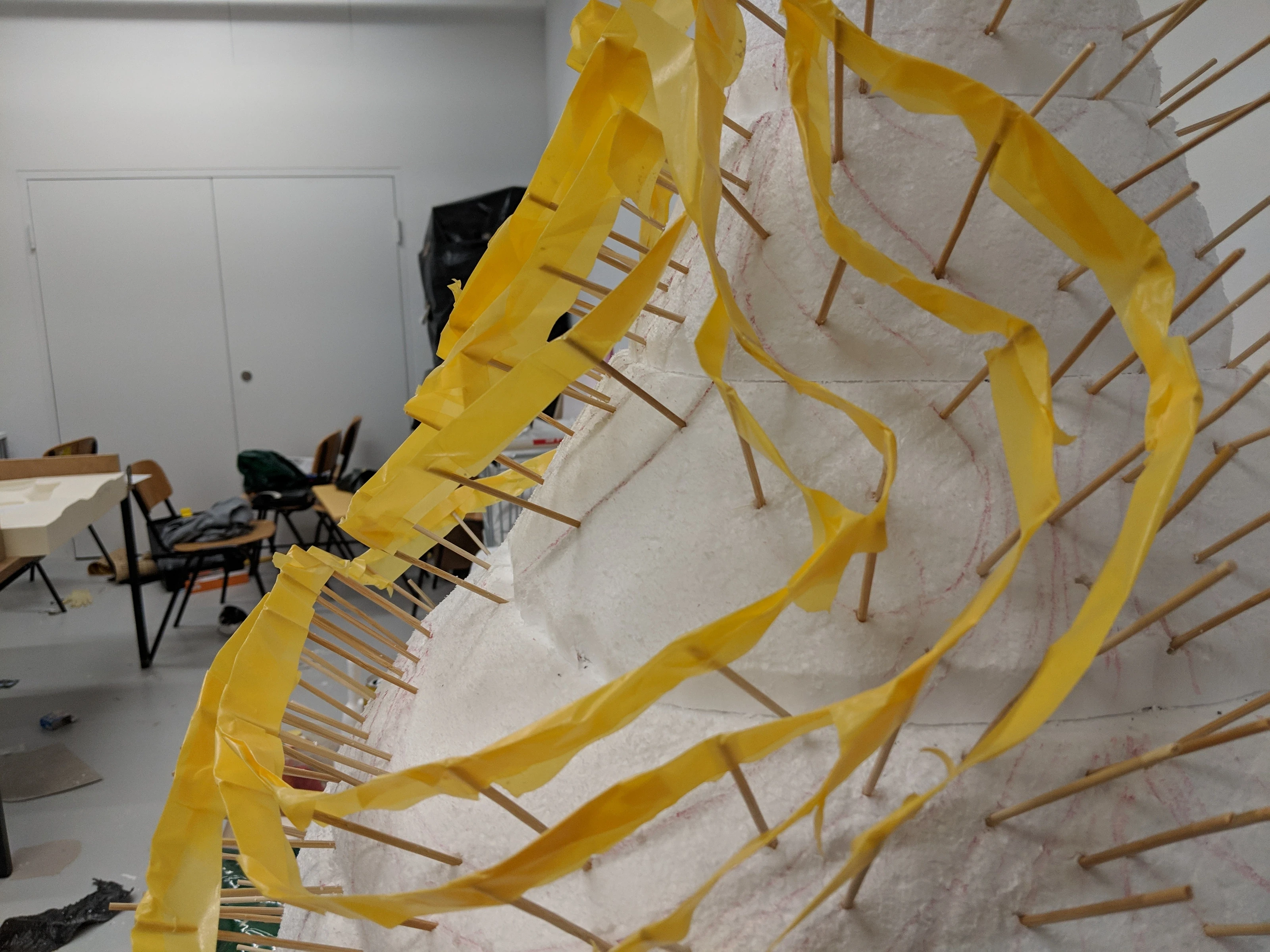 Strips of yellow tape stretched between wooden sticks as temporary ribs.